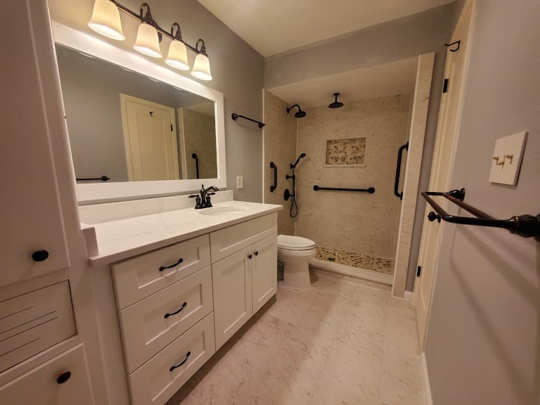 Completed accessible bathroom remodel with a walk-in shower, vanity, and safety rails